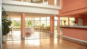 Eine geräumige Hotelhalle mit hoher Decke, einem Balkon und einer Rezeption.