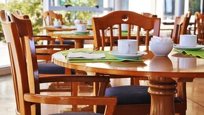 Ein Essbereich mit Holztischen und -stühlen, einer weißen Schüssel und einer Tasse auf einer grünen Tischmatte.