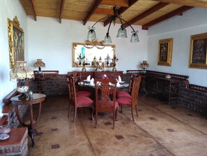 A dining area with a wooden ceiling, a chandelier, and a brick wall. - Casa Hacienda Nasca Oasis (Nazca)