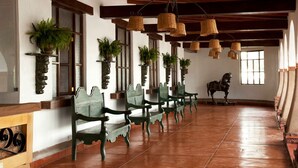 A long corridor with green benches, potted plants, and a horse statue. - Casa Hacienda Nasca Oasis (Nazca)