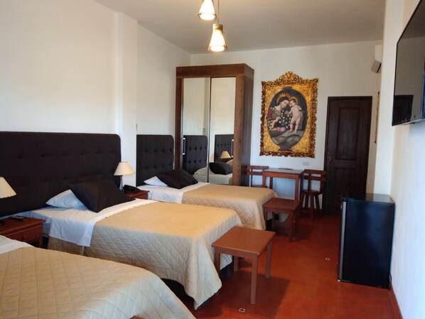 Habitación de hotel con dos camas, un escritorio, una silla, un televisor y un espejo grande.