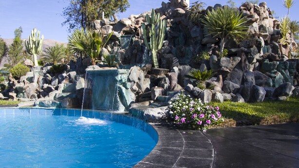 A pool with a waterfall, surrounded by rocks and cacti. - Casa Hacienda Nasca Oasis (Nazca)
