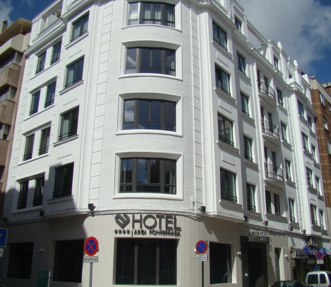 Un hotel de varios pisos con fachada blanca, múltiples balcones y un cartel que indica que es un hotel.