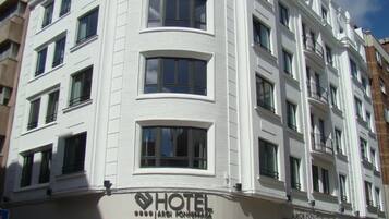 Un hotel de varios pisos con fachada blanca, múltiples balcones y un cartel que indica que es un hotel.
