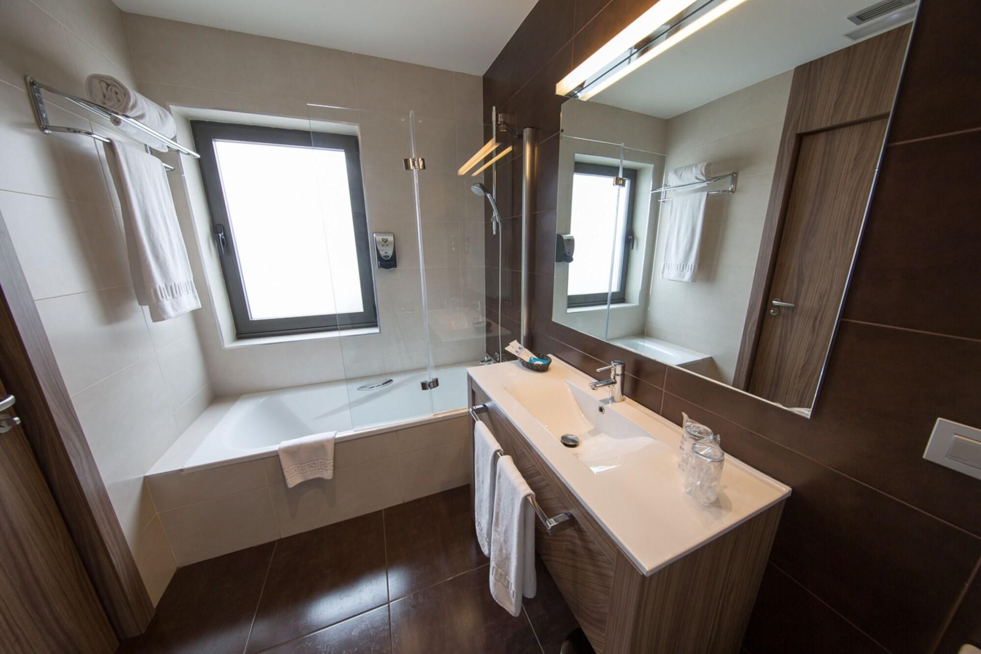 A modern bathroom with a bathtub, a vanity with a mirror, and a window.