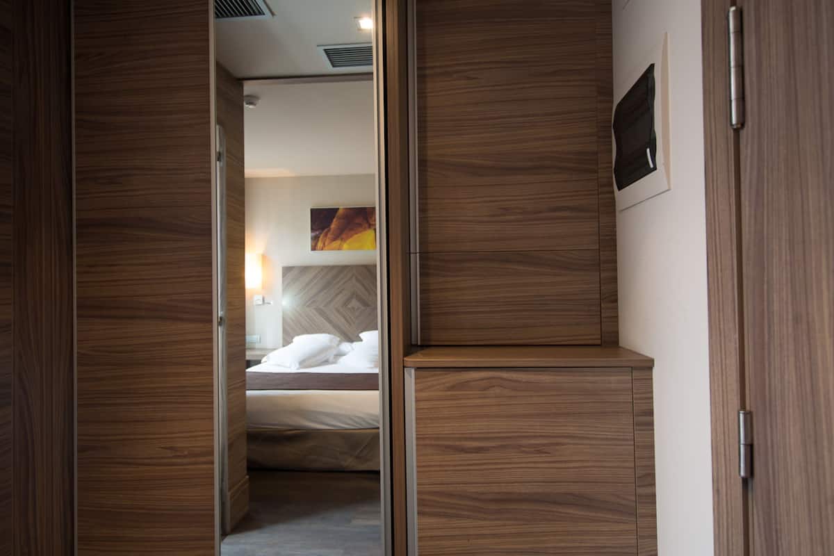 A bedroom with a bed, wooden wardrobe, and a nightstand.