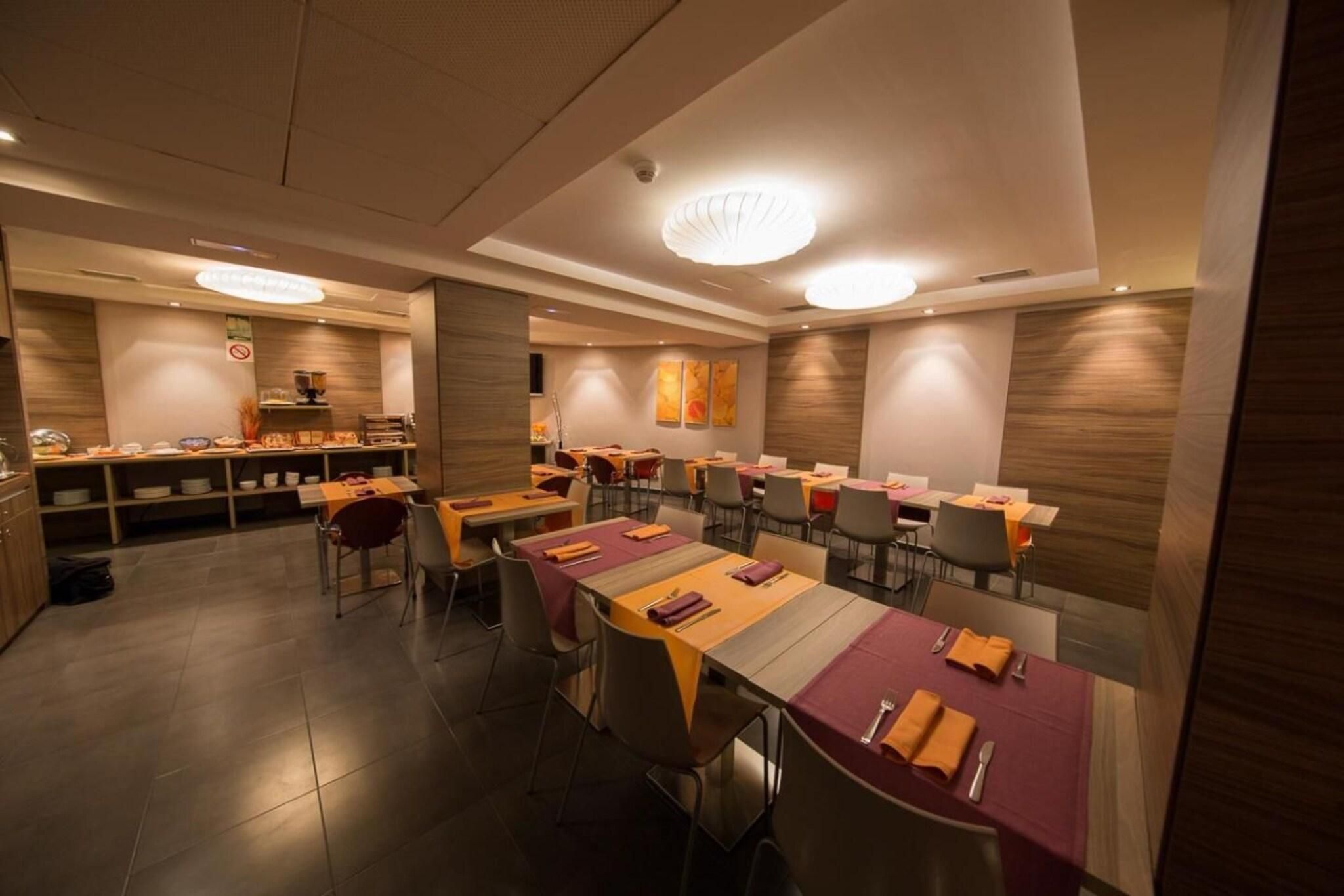 A restaurant with multiple tables, chairs, and a kitchen area.