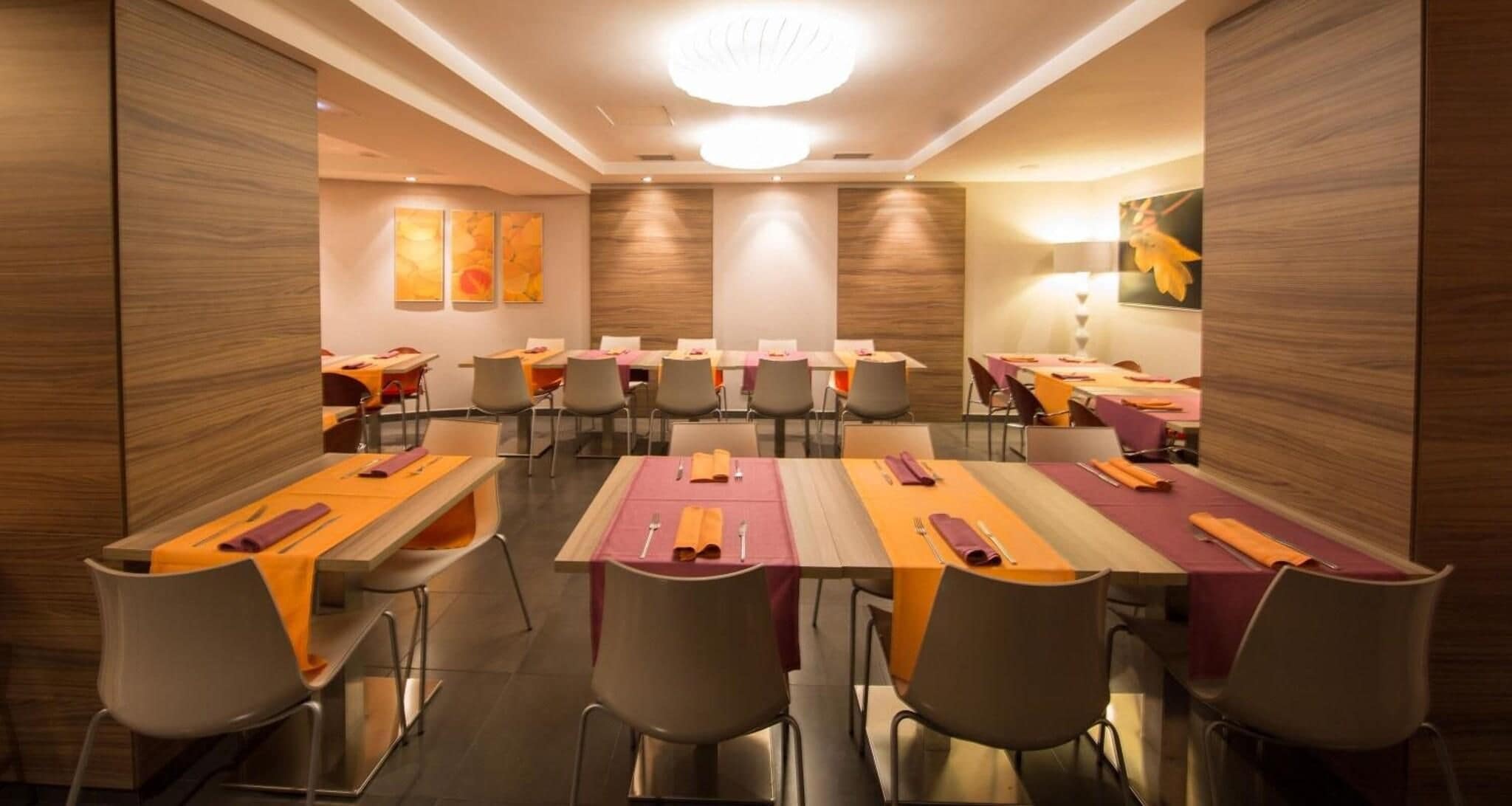 Un salón de conferencias con varias mesas, sillas y una lámpara de techo moderna.