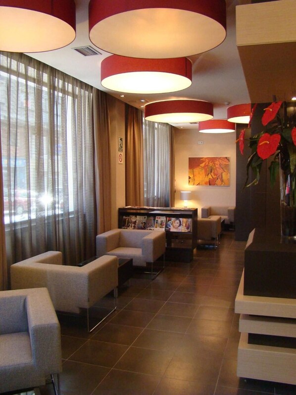 A hotel lobby with a seating area, a reception desk, and a large window with curtains. - Aroi Ponferrada (Ponferrada)