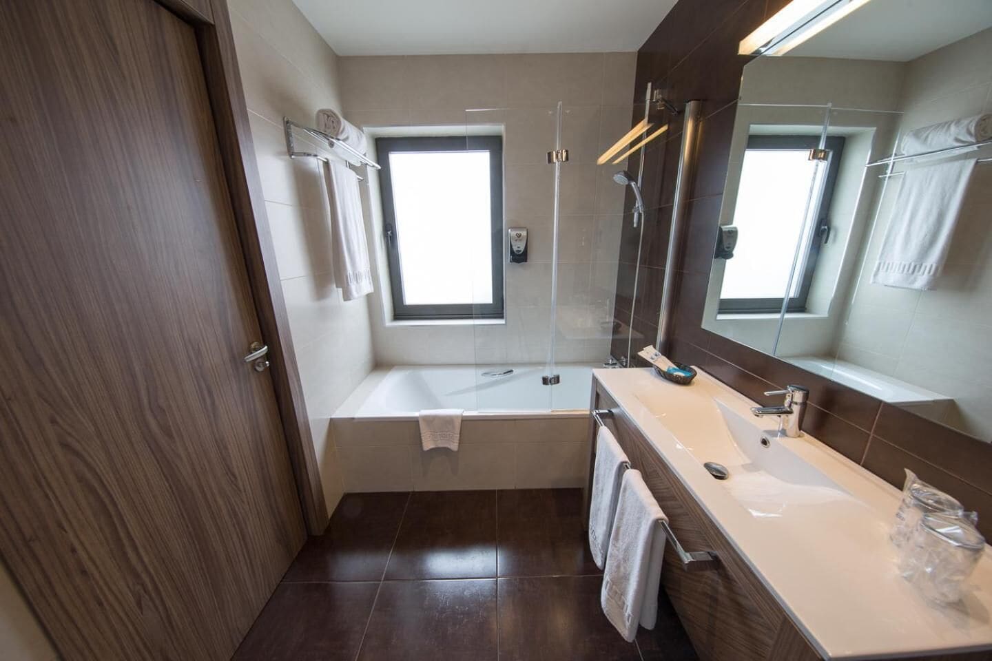 Un baño moderno con una bañera, un espejo grande y una ventana.