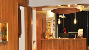 Un área de recepción con un mostrador de madera, una silla roja y una planta.