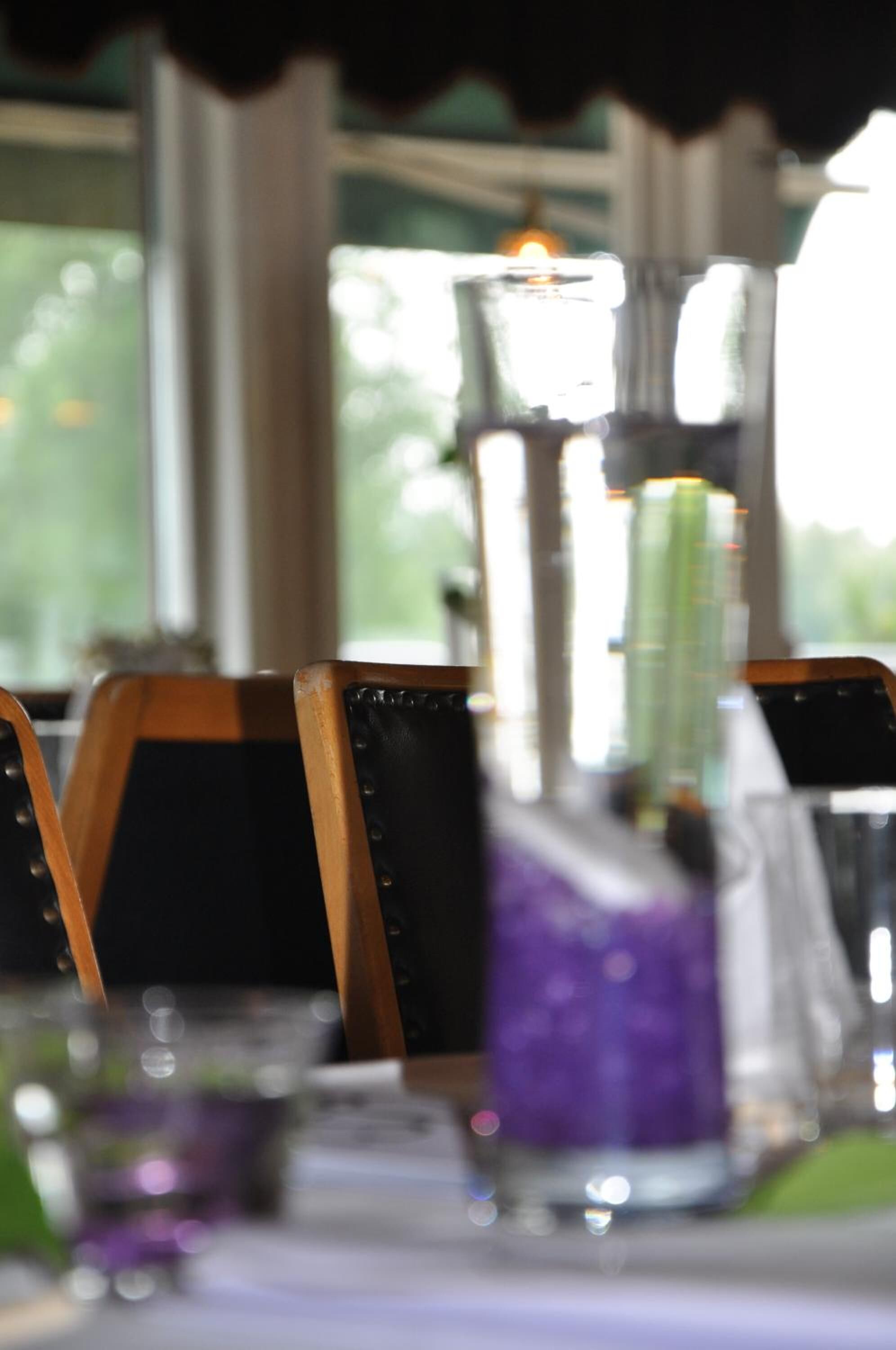 A table with a glass bottle, a purple glass, and a candle.