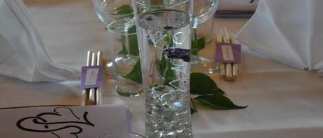 A table set with clear glassware, white napkins, and small purple tags.
