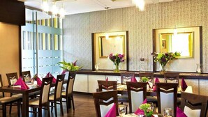 Um restaurante com decoração moderna, apresentando um balcão comprido com diversos arranjos de assentos e composições florais decorativas.