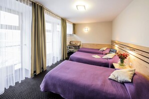 Una habitación de hotel con dos camas, un escritorio y una ventana con cortinas.