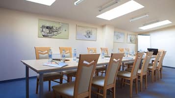 Uma sala de conferências com uma mesa comprida, cadeiras e obras de arte nas paredes.