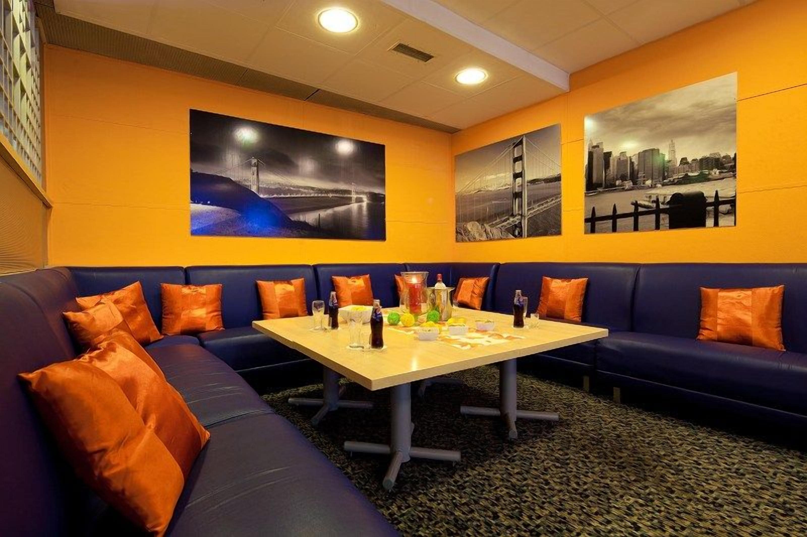 A conference room with a long table, blue and orange seating, and cityscape artwork on the walls.