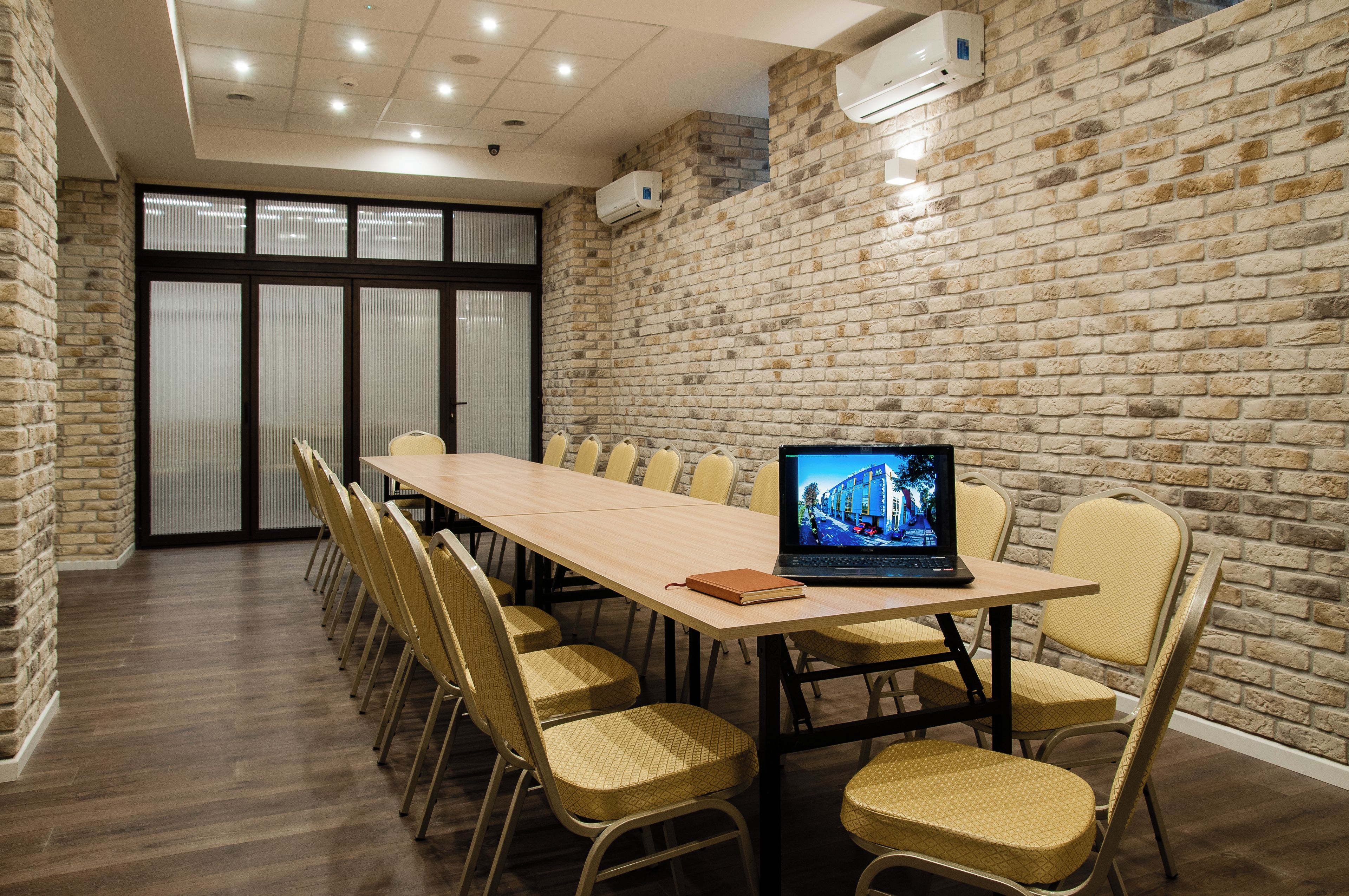 A conference room with a long table, chairs, and a laptop displaying a building image.