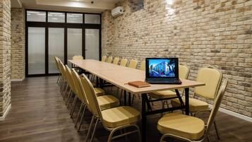 A conference room with a long table, chairs, and a laptop displaying a building image.