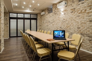 A conference room with a long table, chairs, and a laptop displaying a building image. - Hotel Wilga (Kraków)