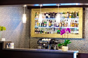 A bar area with shelves of liquor bottles, a coffee machine, and a potted plant. - Hotel Wilga (Kraków)