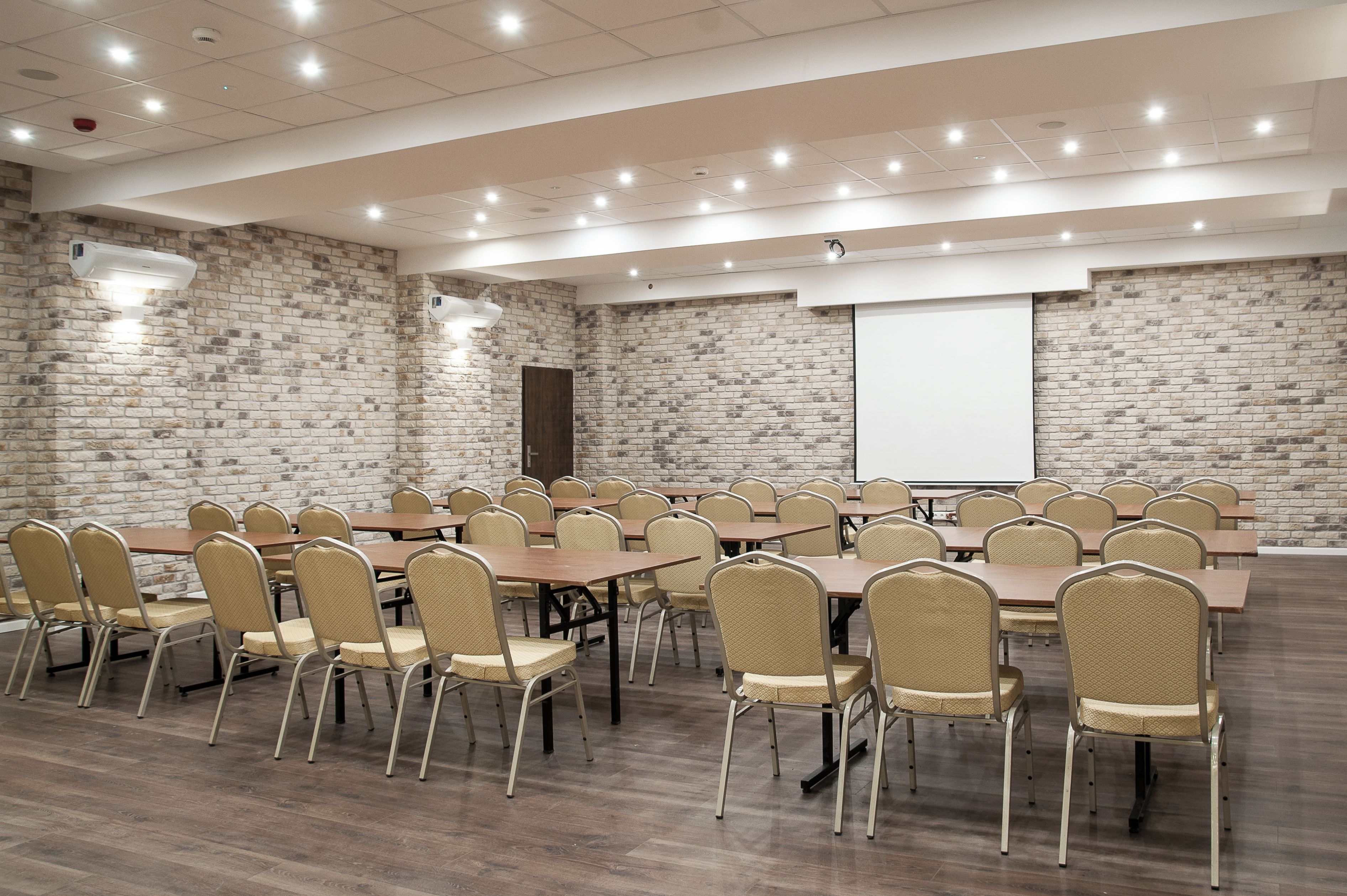 A conference room with a brick wall, multiple tables, and chairs.