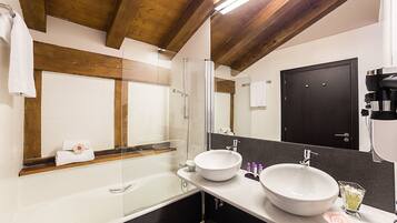 A modern bathroom with two large sinks, a bathtub, and a shower.
