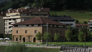 Un edificio con fachada de piedra, varias ventanas y techo plano.