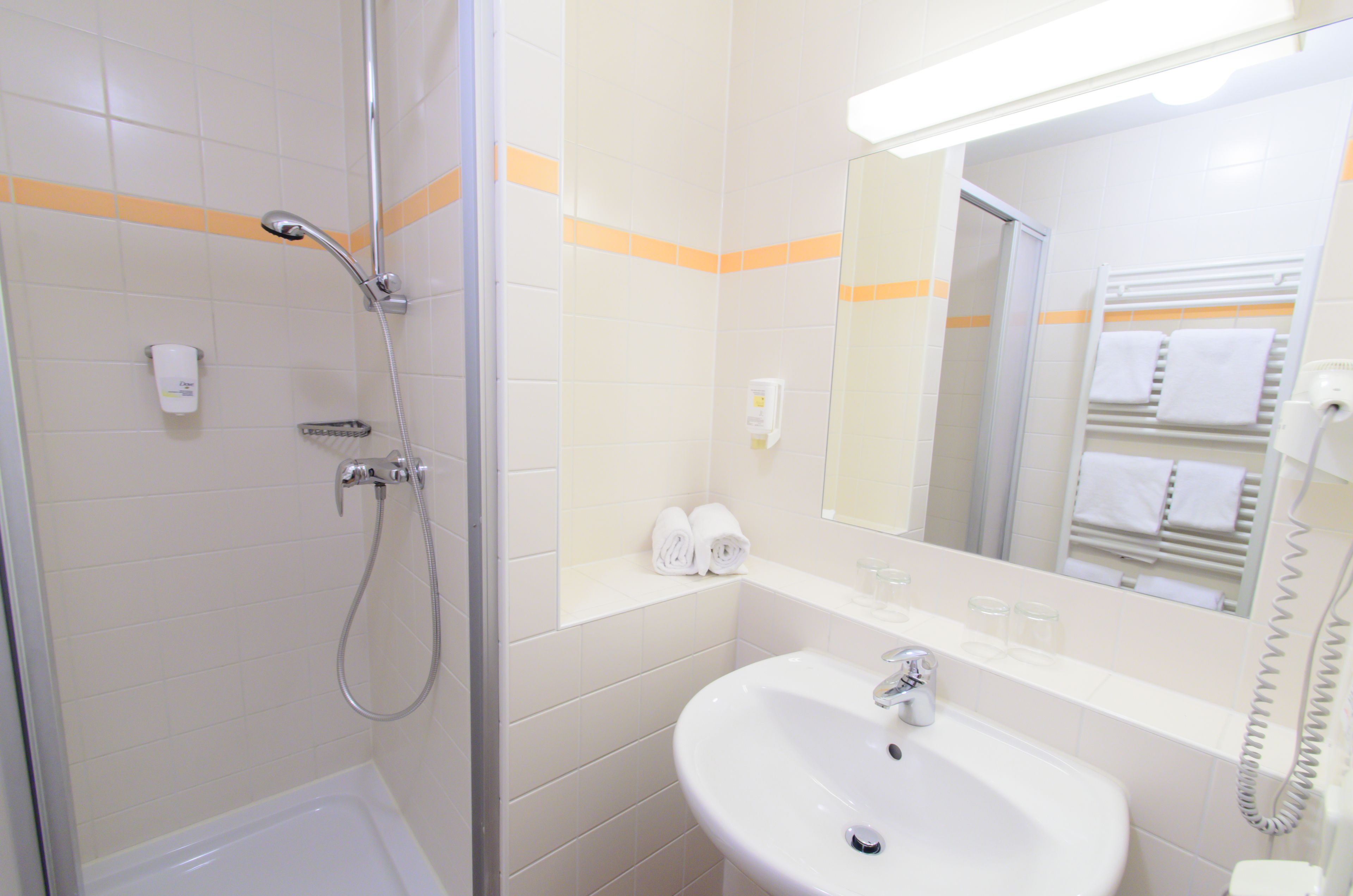 A bathroom with a shower, sink, and mirror.