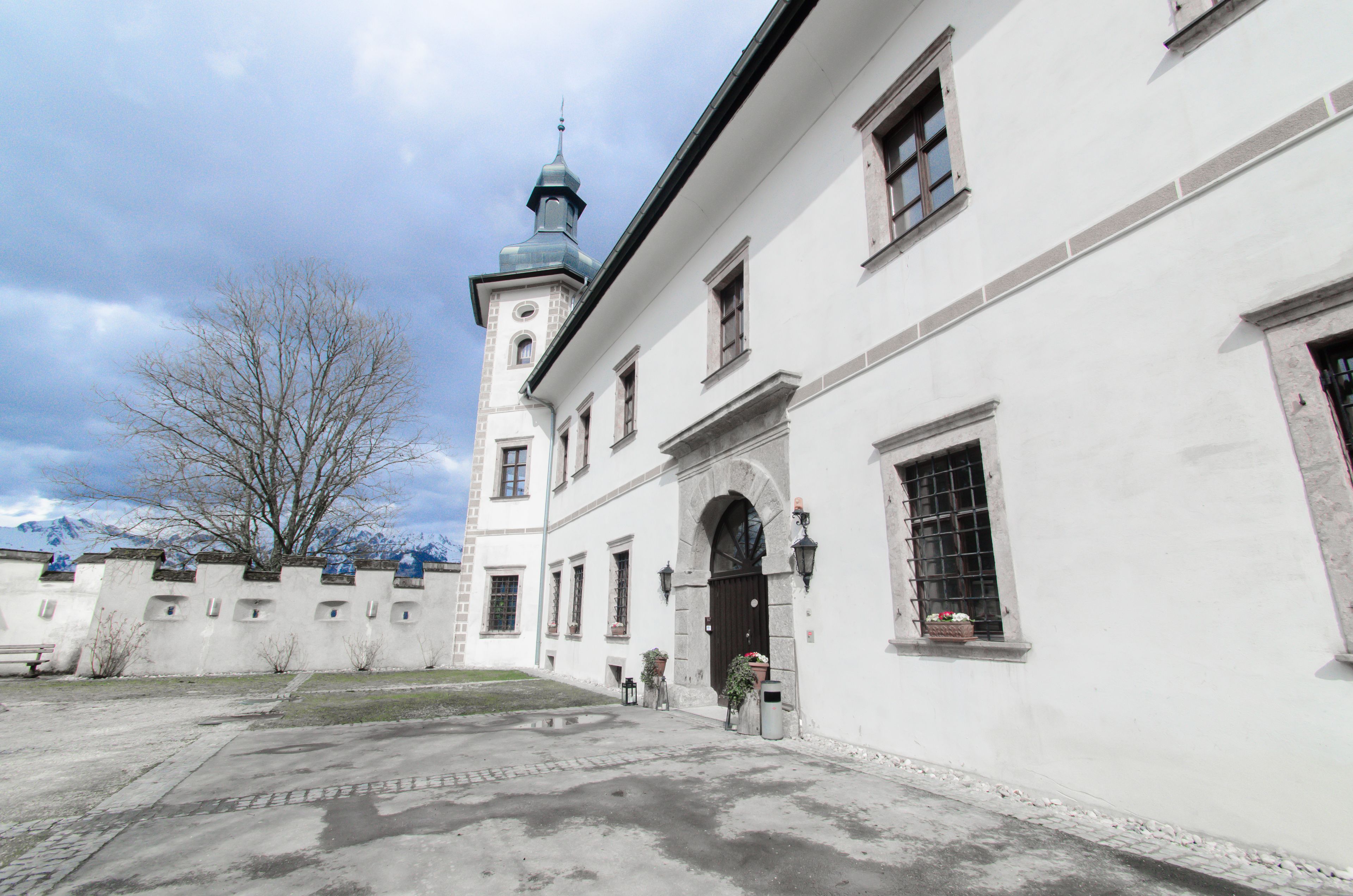 A historic building with a tower, arched entrance, and a courtyard.