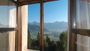 A room with a large window offering a view of a mountainous landscape.