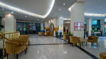 A spacious lobby with a central seating area, a staircase, and a reception desk.