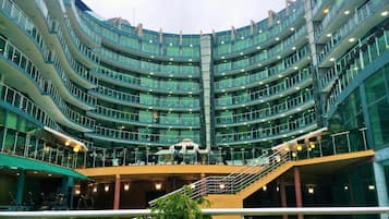 A multi-level hotel with a curved facade, outdoor seating area, and a central staircase.