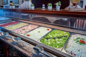Buffet amb diverses opcions gastronòmiques, incloent amanides, pasta i plats de rice.