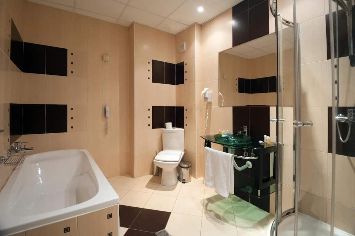 A modern bathroom with a bathtub, toilet, and glass-enclosed shower.