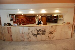 A reception desk with a marble finish, a framed portrait on the wall, and a patterned tapestry.