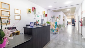 Una zona de recepción con un mostrador oscuro, varios espejos enmarcados y plantas en macetas.