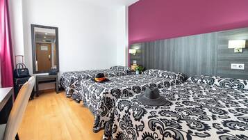 Habitación de hotel con dos camas, un escritorio, un espejo y una puerta.