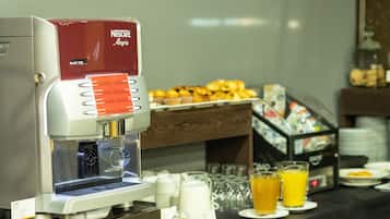 Una máquina de café Nescafé con una variedad de pasteles y bebidas sobre una mesa de buffet.