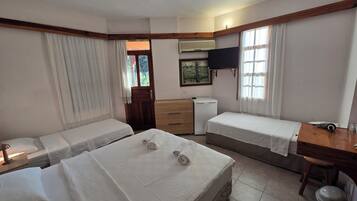 Habitación de hotel con dos camas, un escritorio, un televisor y una ventana.