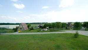 A rural setting with three houses, a grassy field, and a distant body of water. - Hôtel Champ Alsace Aerodrome (Haguenau)