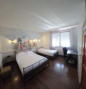 Habitación de hotel con dos camas individuales, un escritorio, una silla, un radiador y un mural con un paisaje urbano.