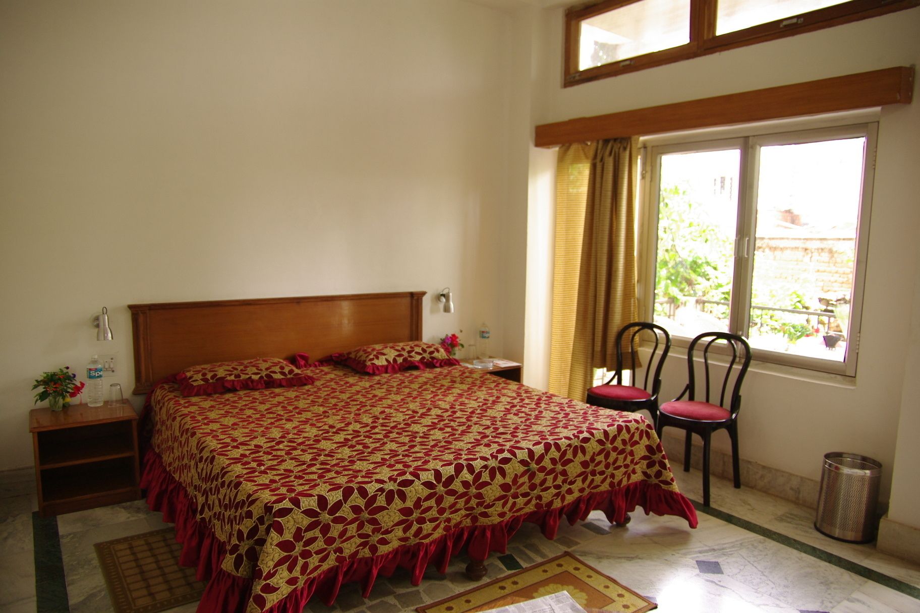 Une chambre à coucher avec un grand lit, une table de chevet, une chaise et une fenêtre avec des rideaux.
