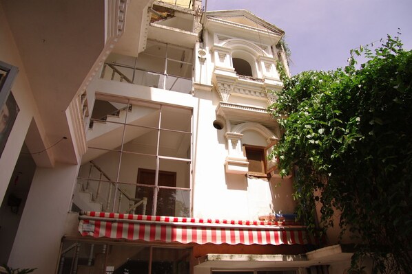 A multi-story building with a balcony featuring a red and white striped awning. - Hotel Zen (Rajnagar)