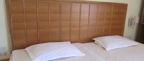 Una cama con cabecera de madera, dos almohadas y una lámpara de noche.