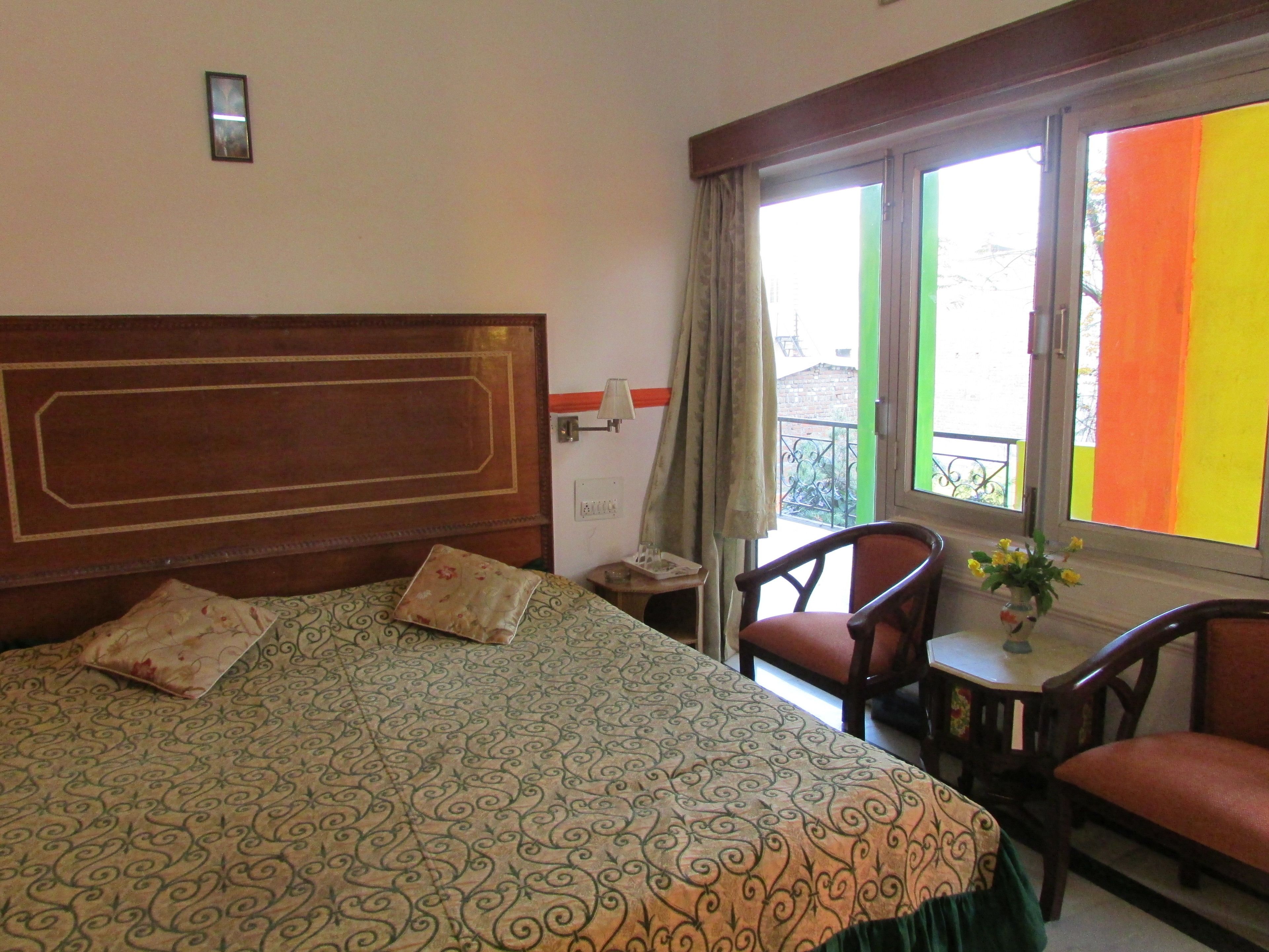 A hotel room with a large bed, a small table with a vase of flowers, and a chair.