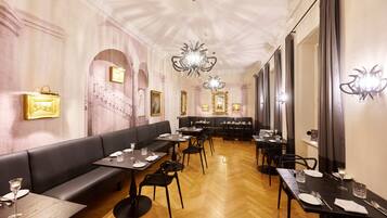 Un restaurant avec un long comptoir, des chaises noires et un lustre.