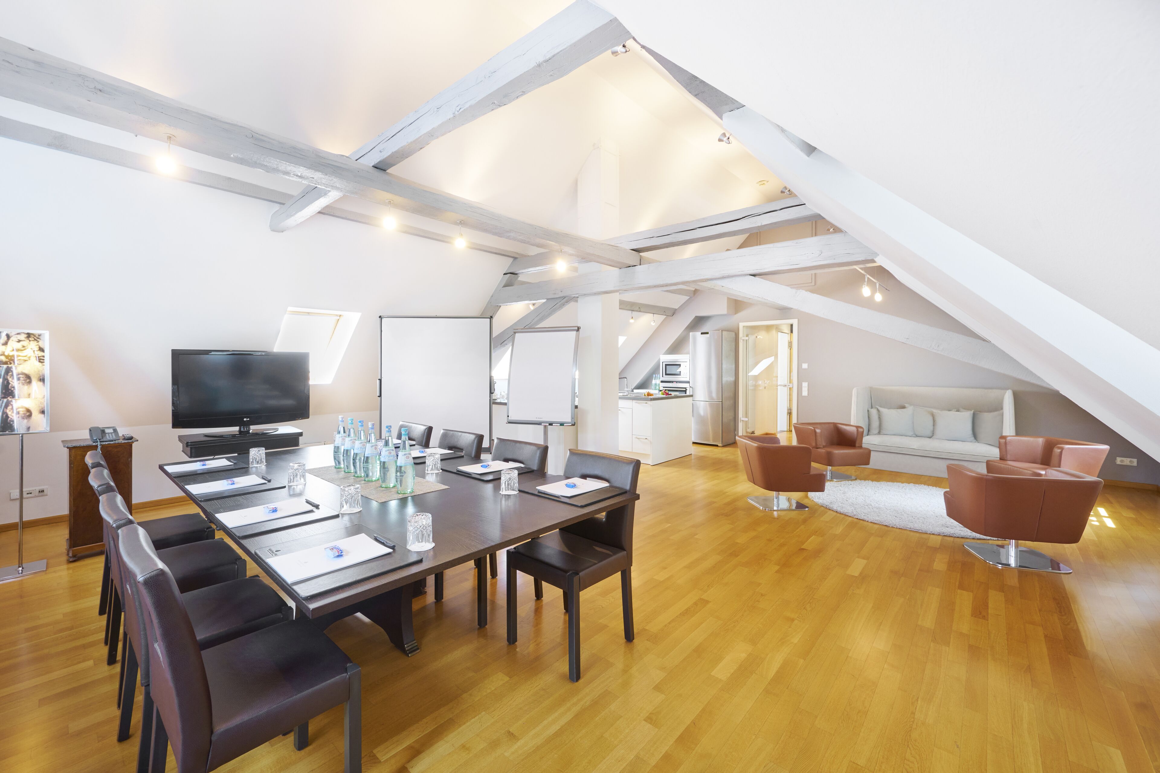 A modern conference room with a long table, chairs, a television, and a whiteboard.