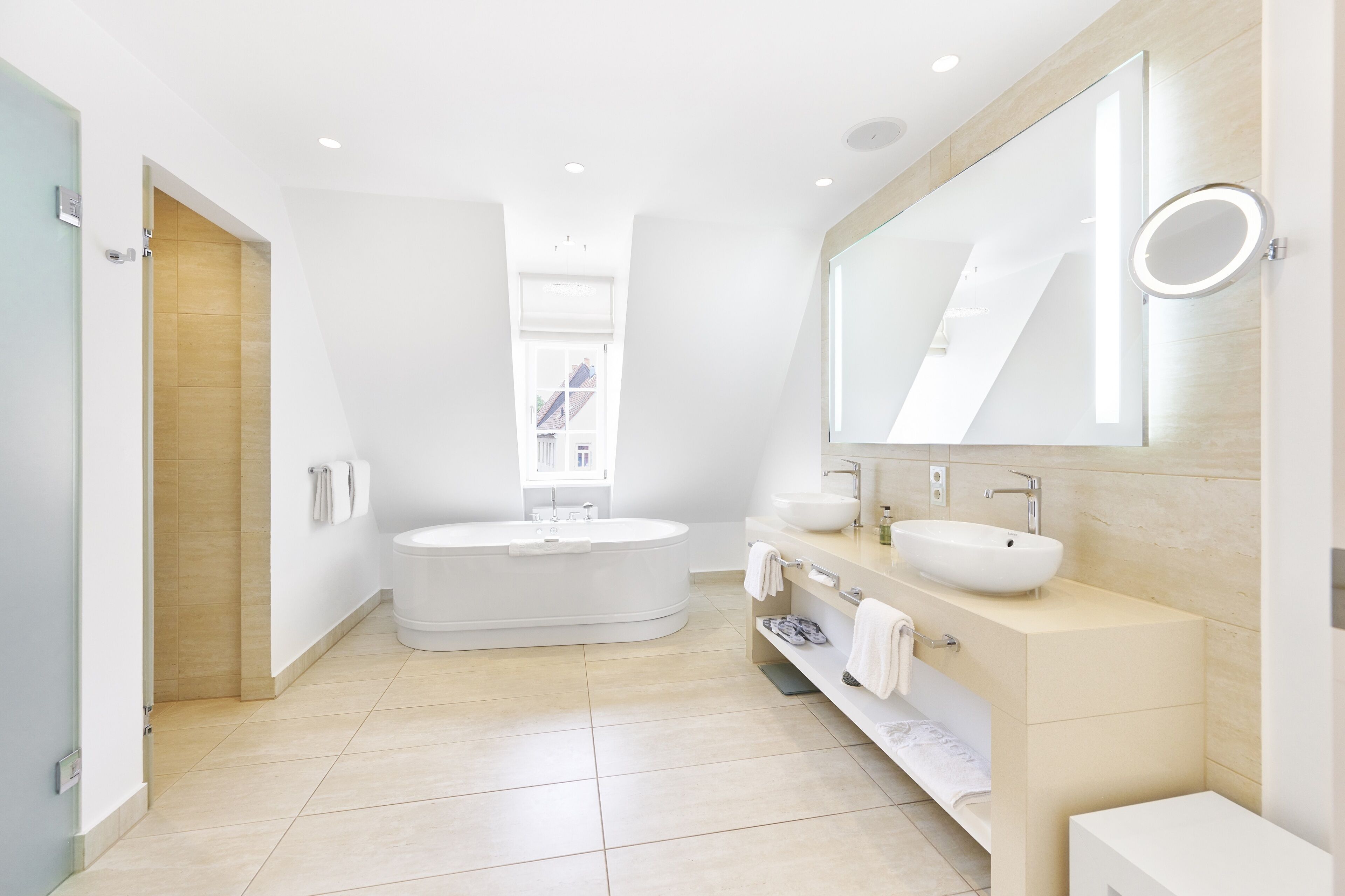 A modern bathroom with a freestanding bathtub, a vanity with a large mirror, and a toilet.