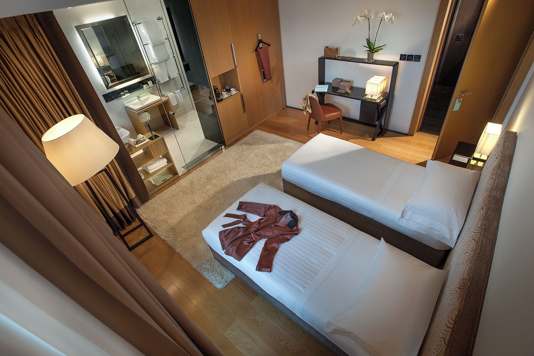 A hotel room with a bed, a desk, a chair, a mirror, a wardrobe, and a bathroom.